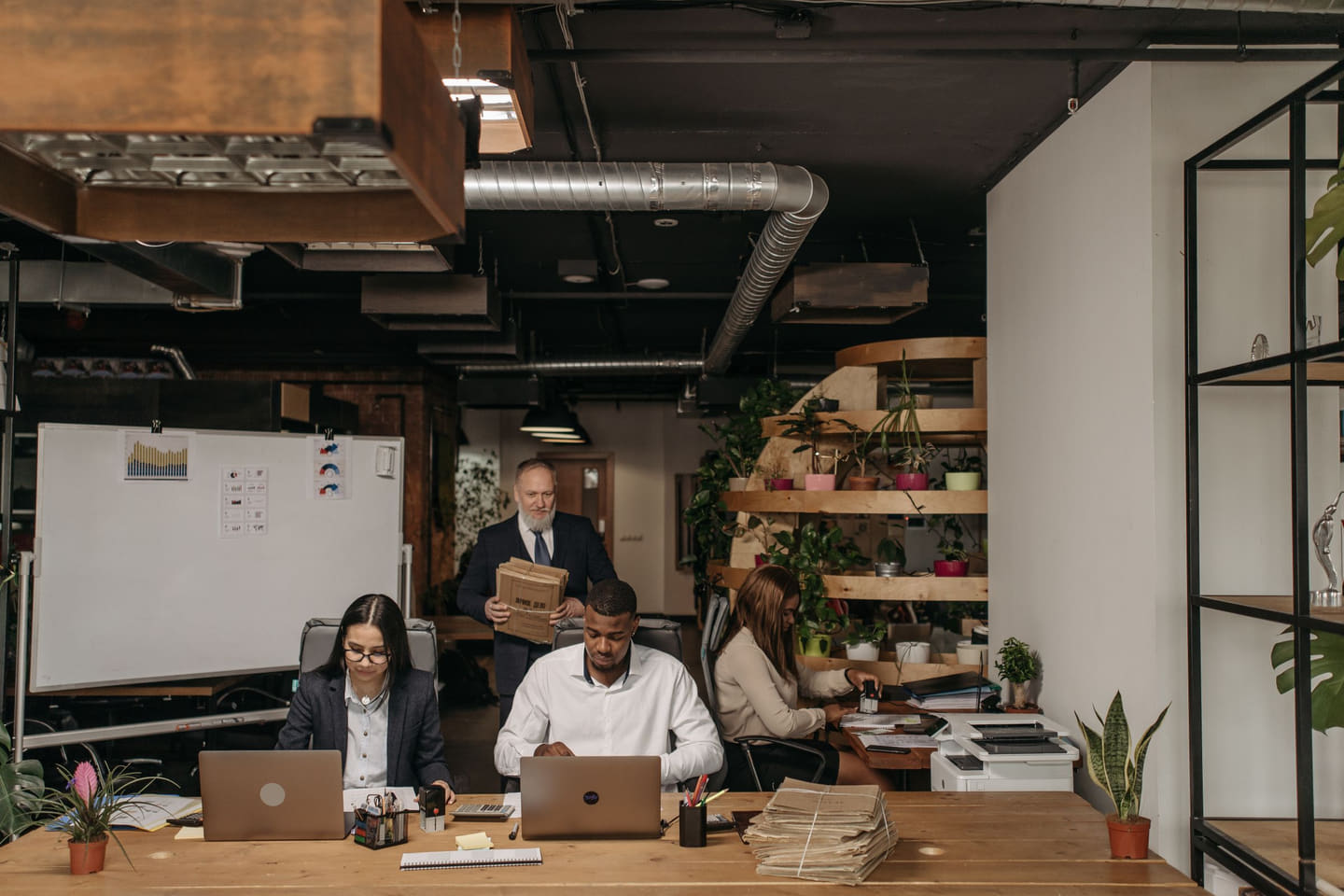 Four staff members working around laptops and files in a shared office